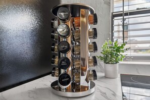 A kitchen with a spice rack containing labeled containers for rosemary, anise, thyme, dill weed, and savory. - Shark Tooth Coastal Retreat (Englewood)