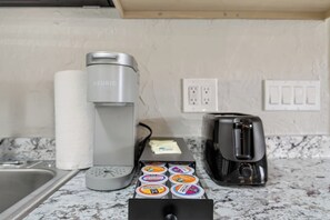 A kitchen with a coffee maker, a toaster, and a container of coffee pods. - Shark Tooth Coastal Retreat 4BR 2BA Sleep 14 (Englewood)