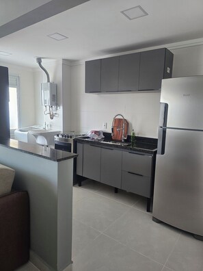 A modern kitchen with grey cabinets, a stainless steel refrigerator, and a built-in oven. - Beautiful Luxury Resort Apartment (Guarujá)