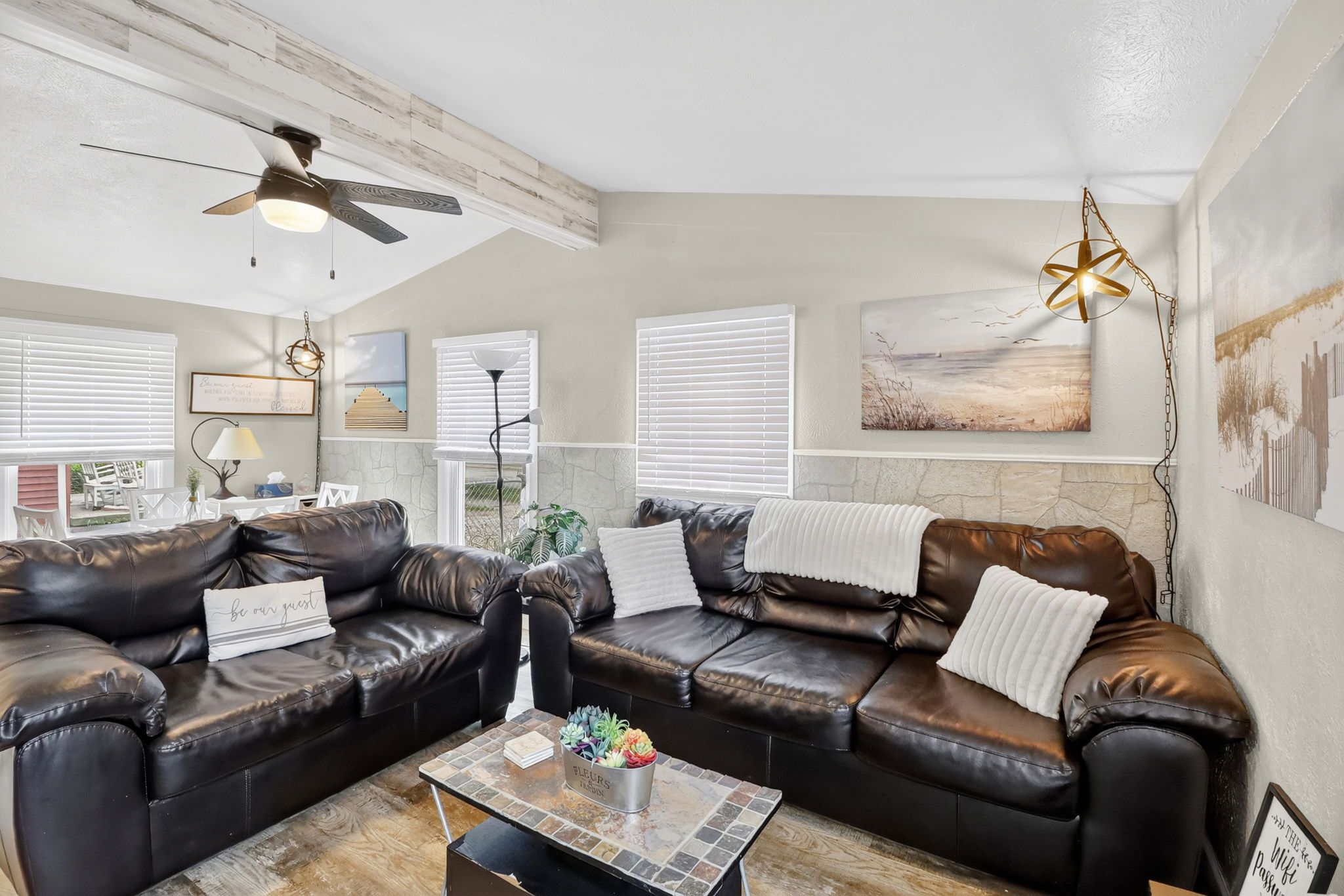 A living room with a sectional sofa, a coffee table, and a ceiling fan.