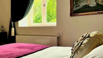 Une chambre à coucher avec un lit, une fenêtre avec des rideaux, un radiateur et un tableau accroché au mur.