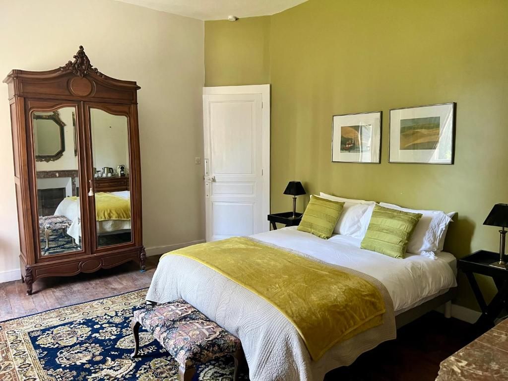 Un dormitorio con cama, mesitas de noche, armario, alfombra y dos cuadros en la pared.