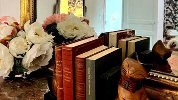 A collection of books, a vase with flowers, and a small statue on a surface.