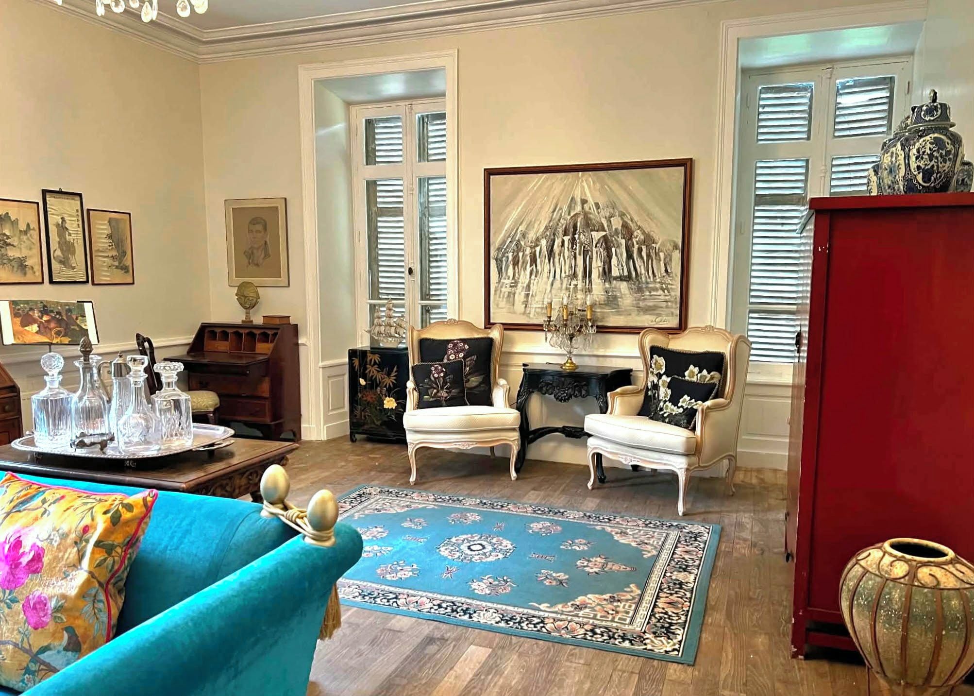 Una sala de estar con un sofá azul, dos sillones, una chimenea y un cuadro grande.