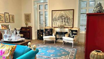 Una sala de estar con un sofá azul, dos sillones, una chimenea y un cuadro grande.