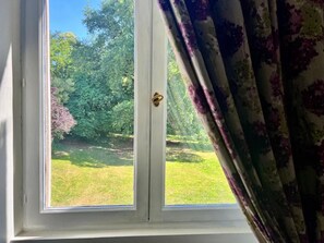 Una ventana con vistas a un jardín y árboles.