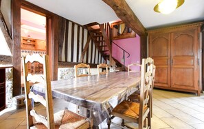 A dining area with a wooden table and chairs, a staircase, and a large wooden cabinet. - Awesome home in Saint-André d'Hébertot with WiFi (Saint-André d'Hébertot)