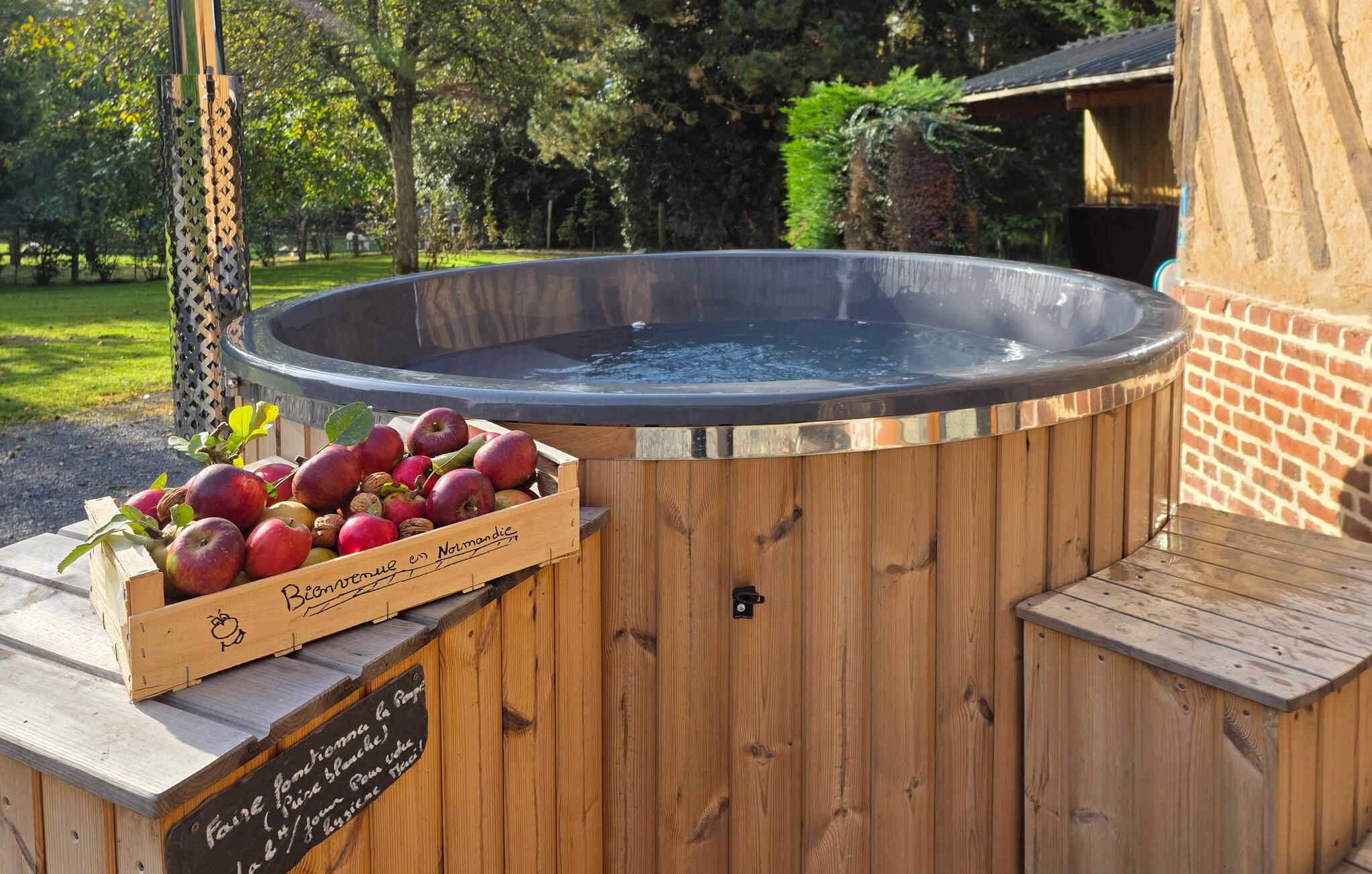 Ein Whirlpool mit einer Holterrasse und einer Holzkiste mit Äpfeln und Walnüssen.