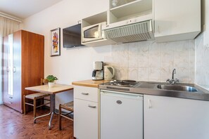 A compact kitchenette with a stove, microwave, and coffee maker. - A5 - Apartment w pool, terrace and sea view (Dugi Rat)