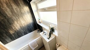 Ein Badezimmer mit einer Badewanne, einem Waschbecken, einer Toilette und einem Fenster mit Blick.