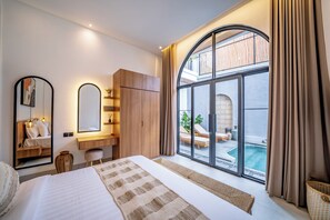 Une chambre d’hôtel moderne dotée d’un grand lit, d’un bureau, d’une armoire et offrant une vue sur une piscine.