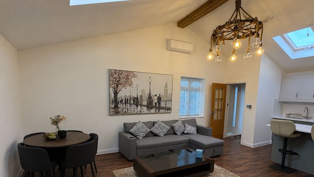Una sala de estar moderna con un sofá gris, una mesa de centro y un comedor con una mesa redonda y sillas.