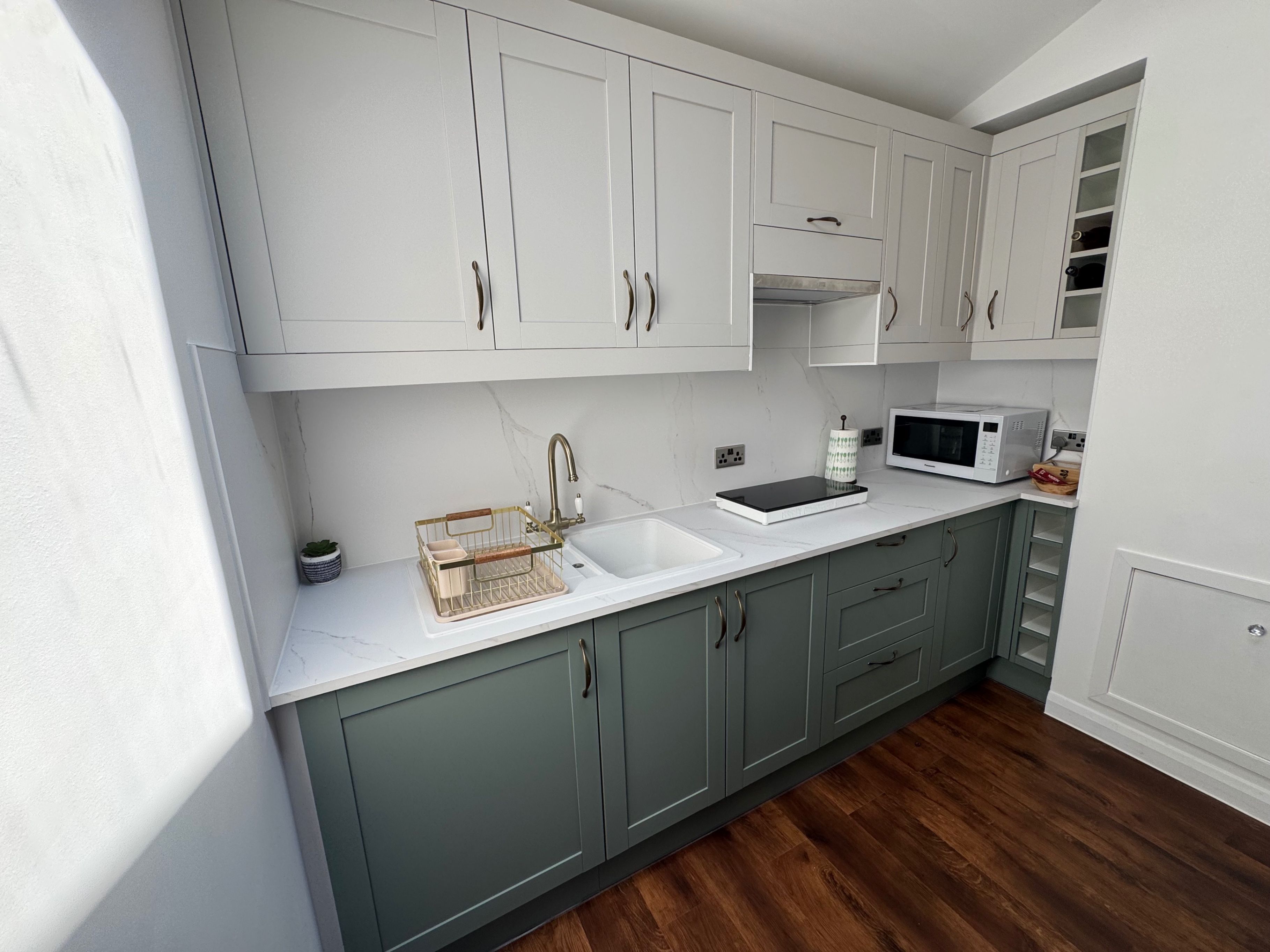 A modern kitchen with white cabinets, a stainless steel sink, and a microwave.