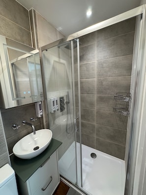 Een moderne badkamer met een douchecabine van glas, een wit wastafelmeubel en een spiegel erboven.