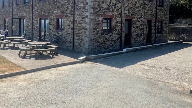 Un edificio de piedra con varias ventanas y un área pavimentada con mesas de picnic.