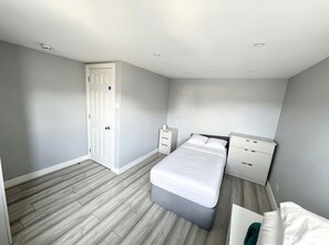 Ein Schlafzimmer mit Bett, Nachttischen, einem Kleiderschrank und einer Tür.