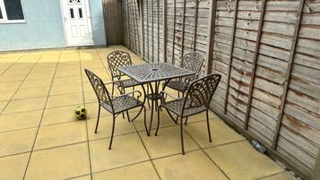 A patio with a table and chairs, a door, and a wooden fence.