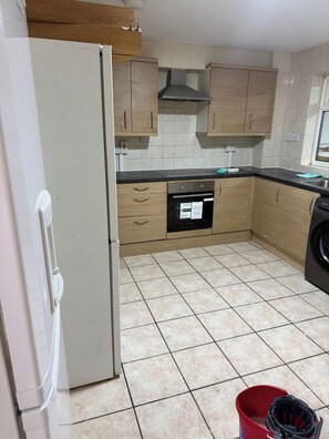 Eine Küche mit Kühlschrank, Backofen und Waschmaschine.