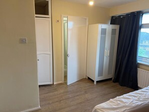 Ein Schlafzimmer mit einem Bett, einem Kleiderschrank und einer Tür zu einem Badezimmer.