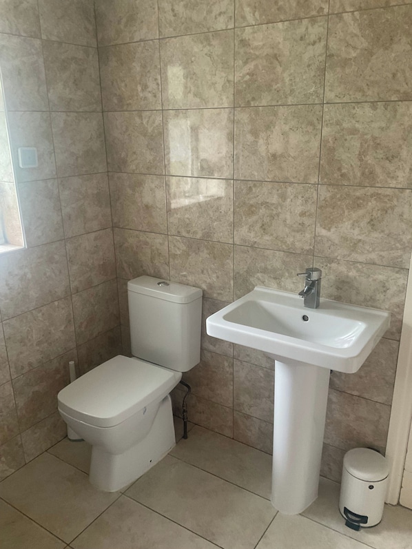 Une salle de bain équipée de toilettes, d’un lavabo et d’une poubelle.
