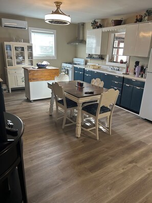 A kitchen with a dining table, chairs, a stove, and cabinets.