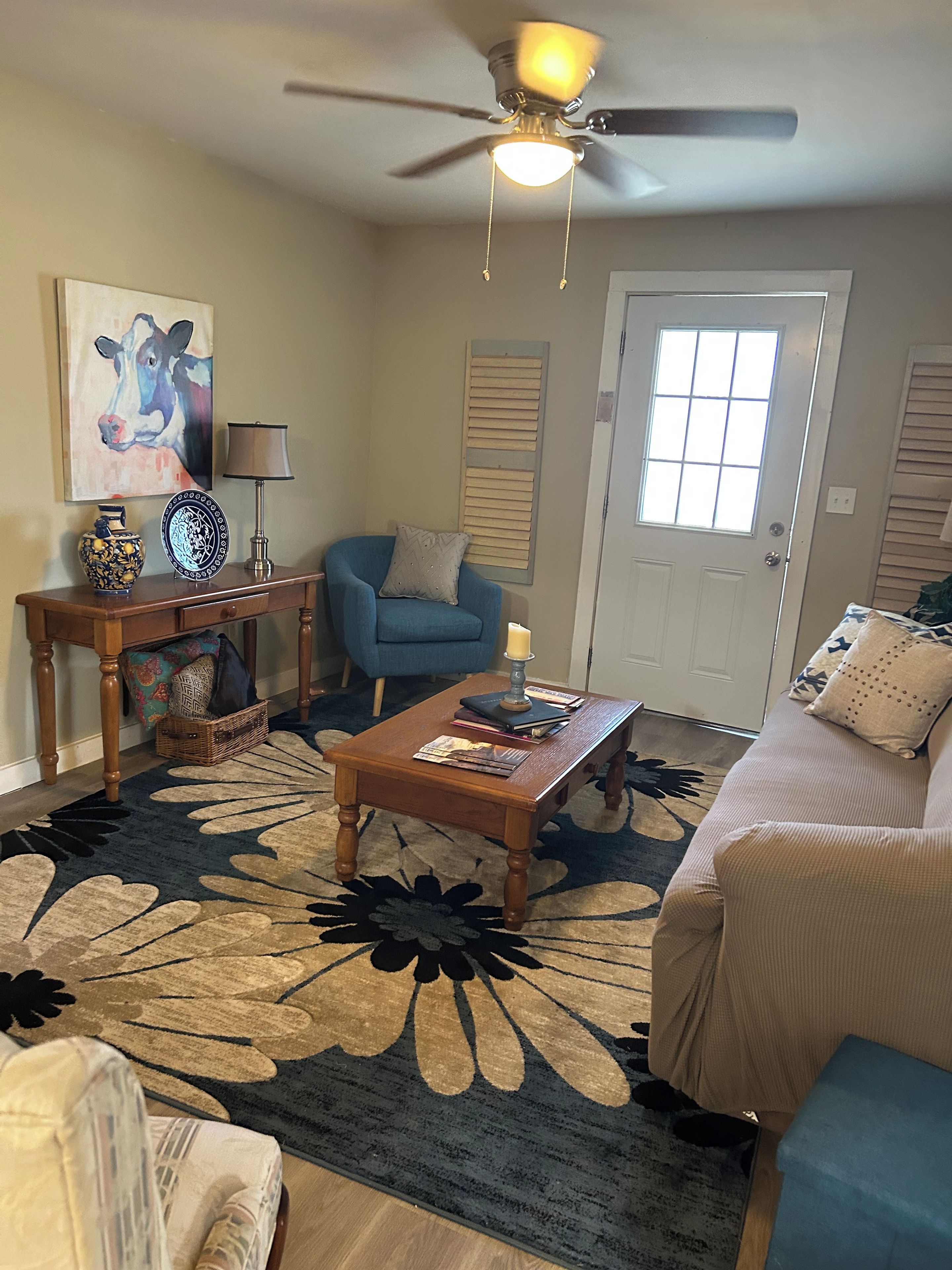 A living room with a ceiling fan, a blue armchair, a coffee table, and a patterned rug.