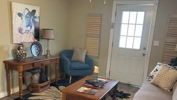 A living room with a ceiling fan, a blue armchair, a coffee table, and a patterned rug.