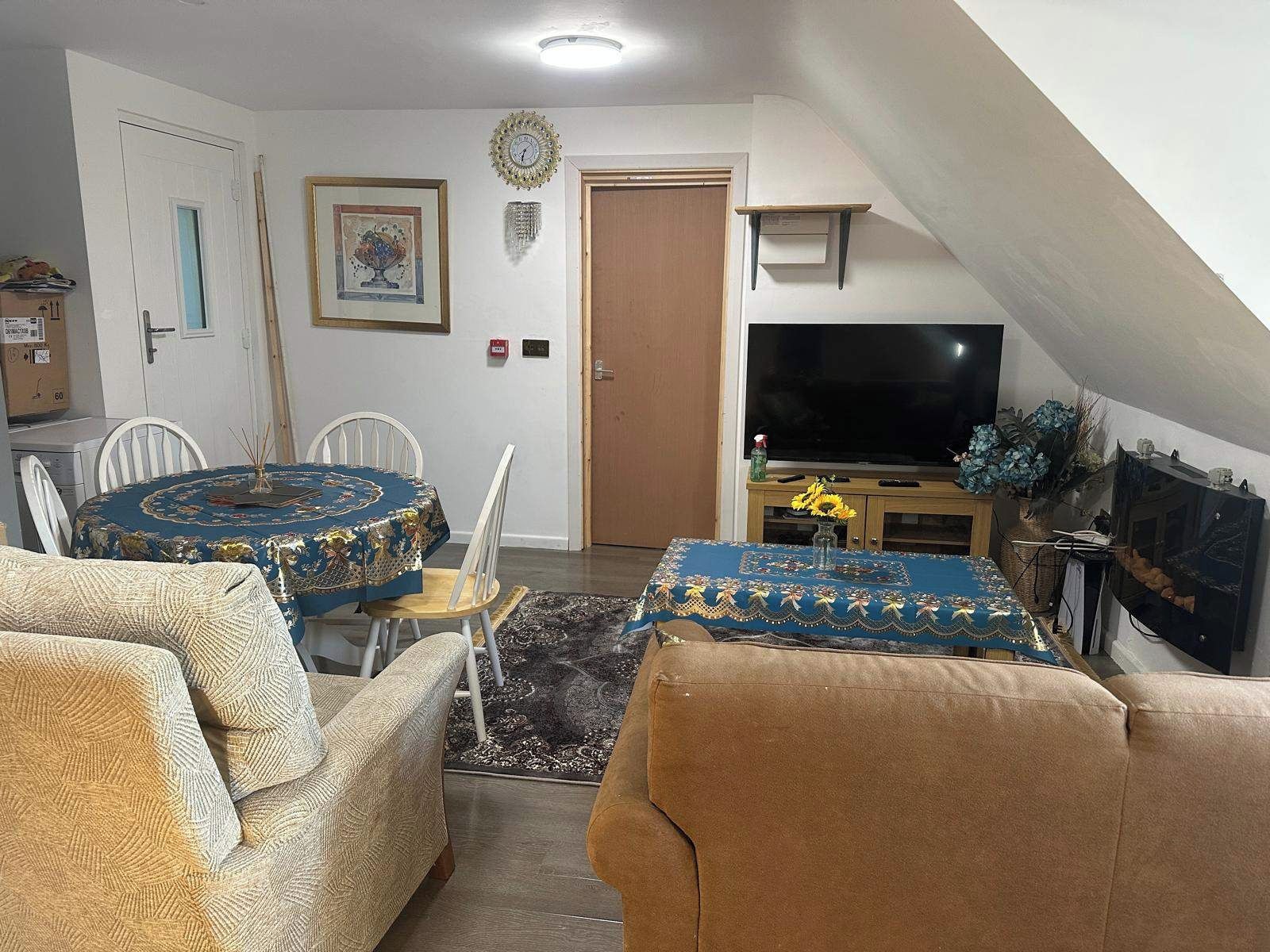 A living room with a dining area, a television, and a staircase.