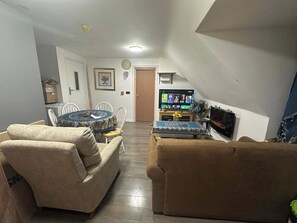 A living room with a sofa, a round coffee table, a television, and a fireplace. - Apartment Sleeps 4 with Parking (Rye)