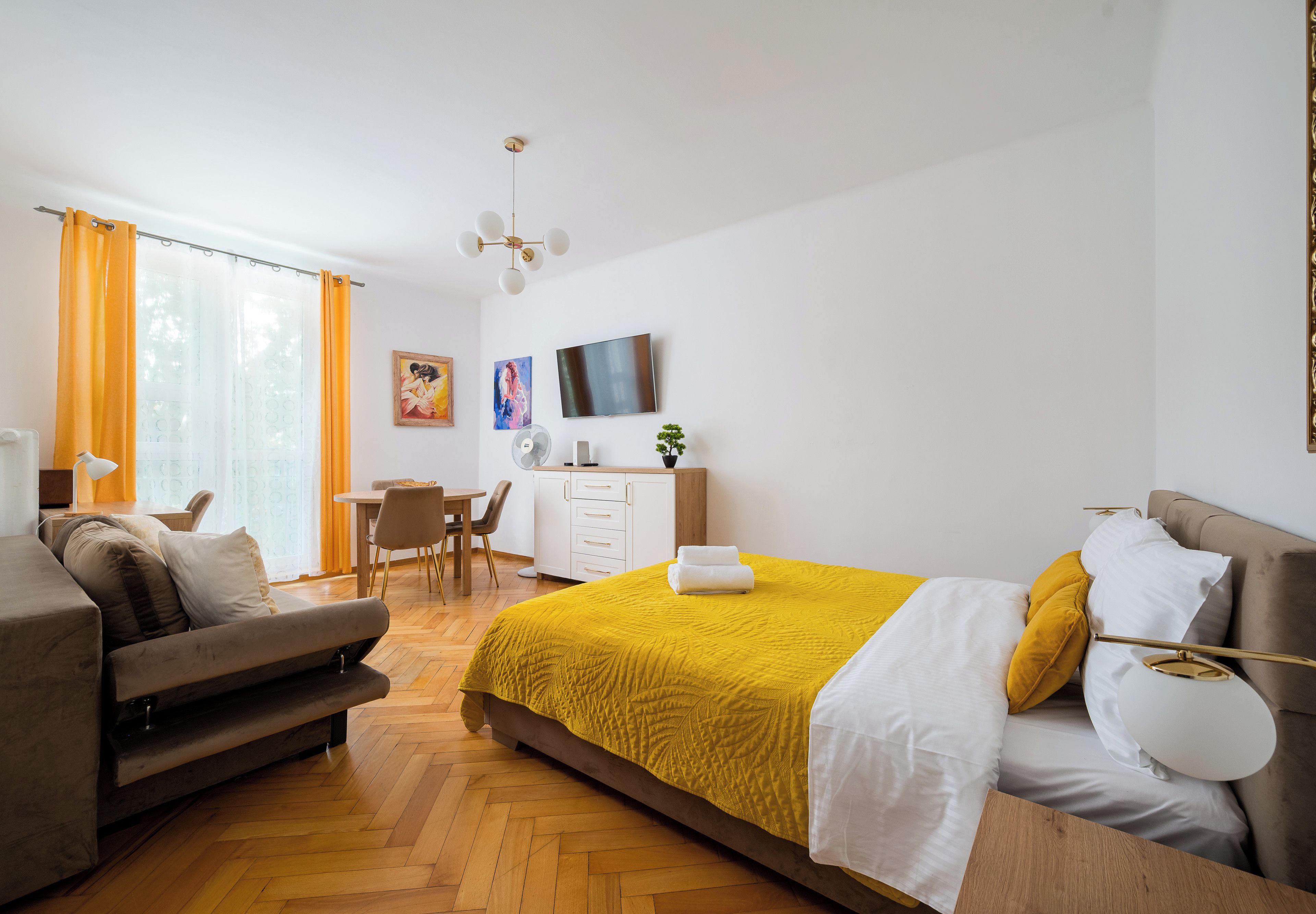 A modern hotel room with a bed, a desk, a chair, and a TV.