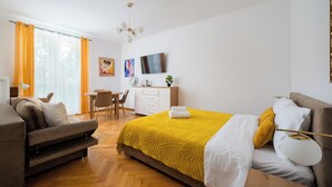 Ett hotellrum med en säng, ett skrivbord, en stol, en soffa och en tv.