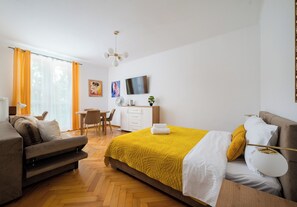 Una habitación de hotel con cama, escritorio, silla, sofá y televisor.