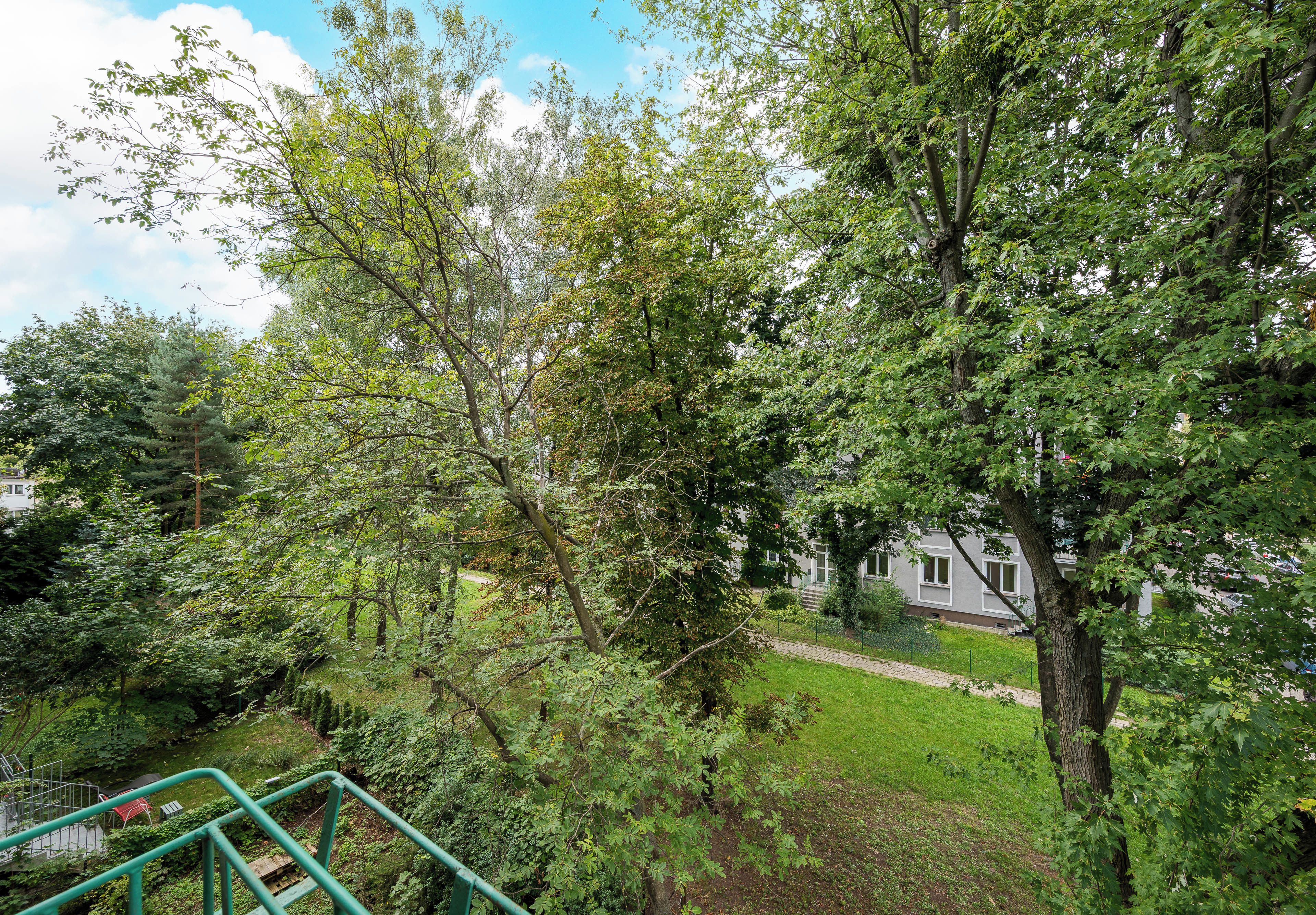 A residential area with a grassy lawn, a pathway, and a building with multiple windows.