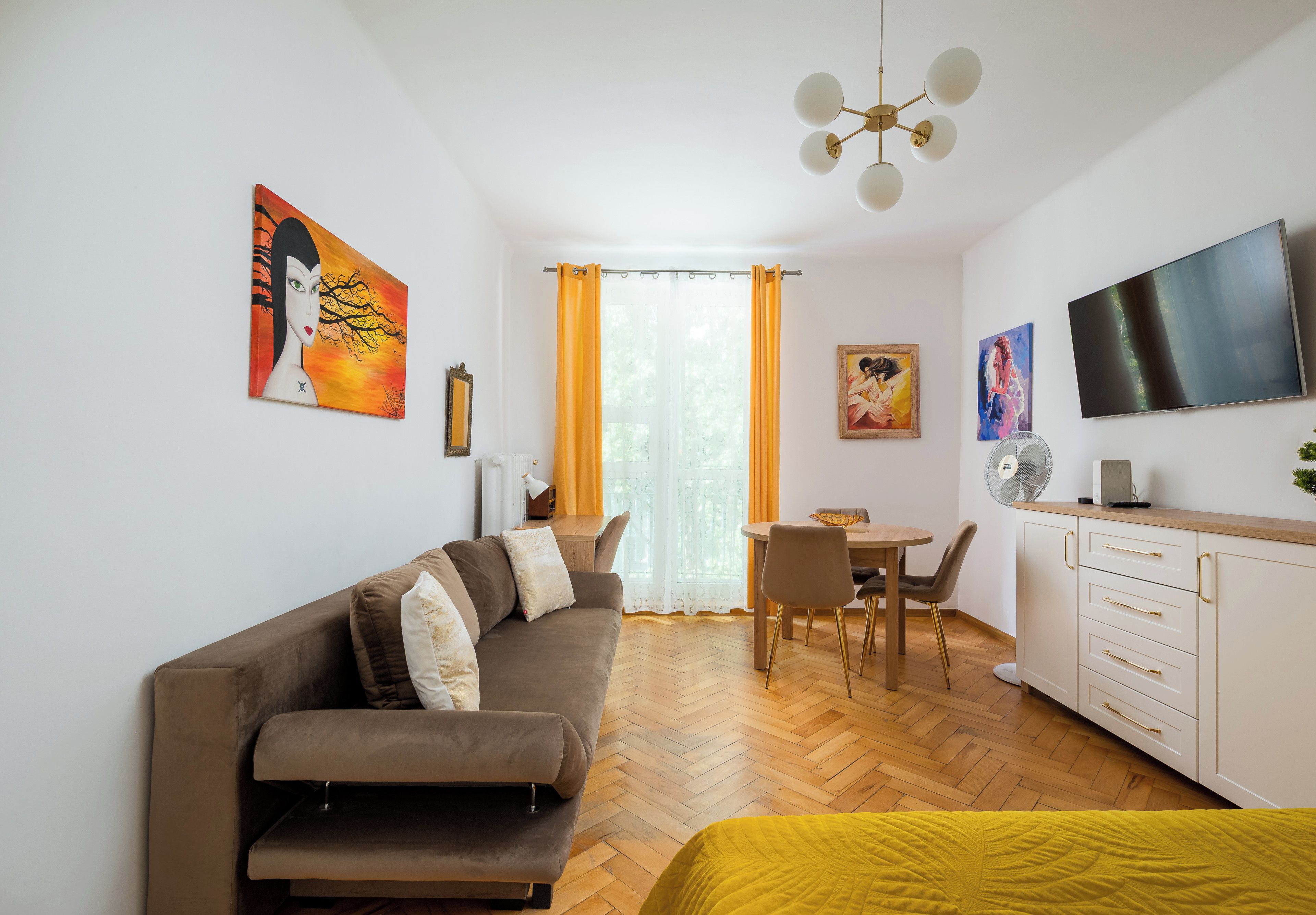 A modern living room with a sofa, dining table, and kitchen area.