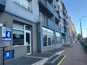 A building with a storefront labeled 'UZOTEKA' and a sign indicating a 4th floor.