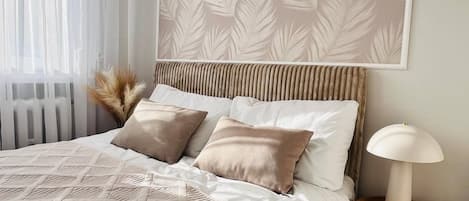A neatly made bed with a patterned bedspread, two pillows, a bedside lamp, and a wall-mounted artwork.