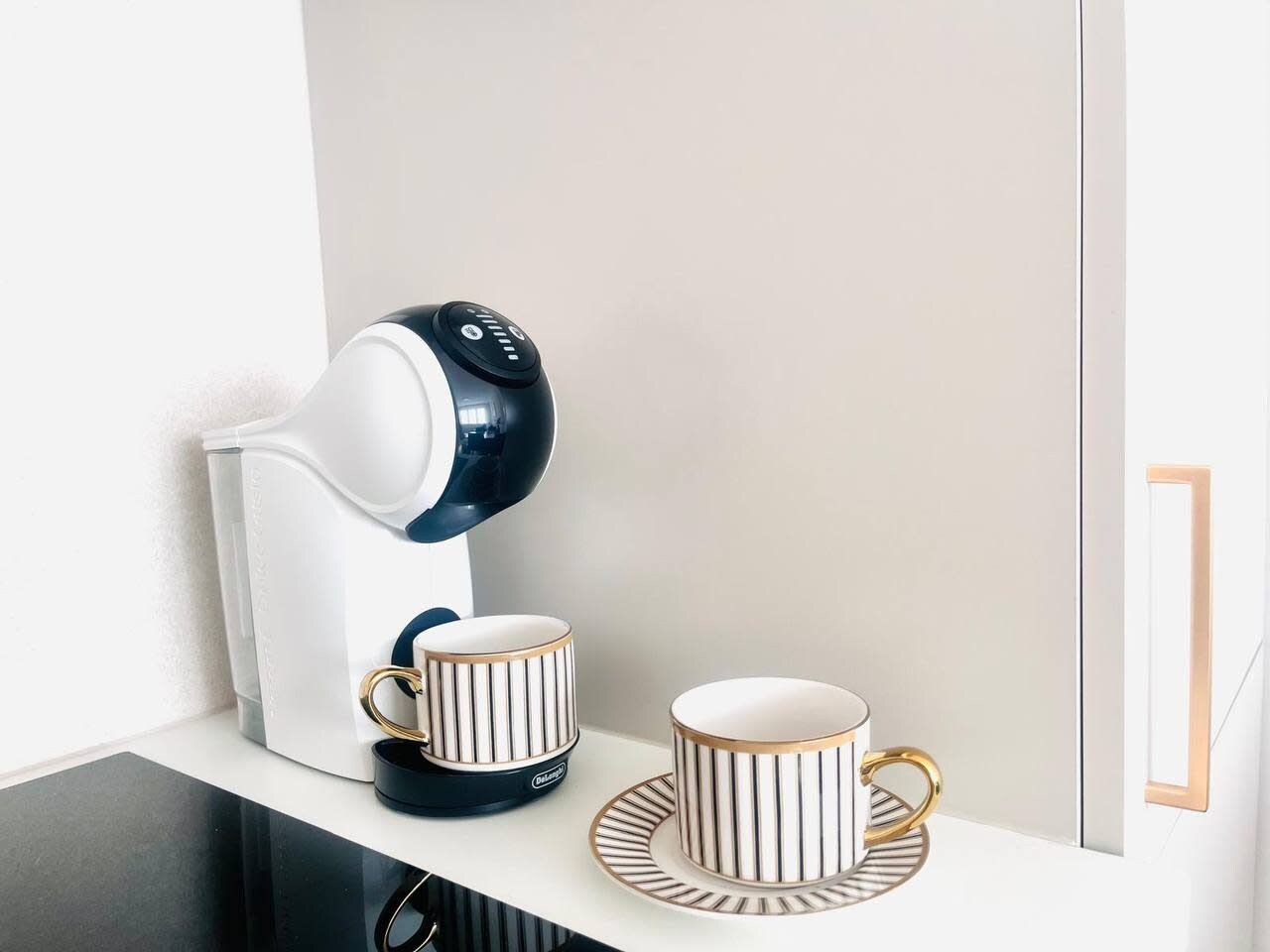 A coffee maker with two cups on a white surface.