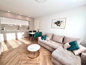 A modern living room with a sofa, a round coffee table, and a dining area with chairs.
