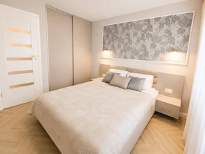 A bedroom with a bed, bedside tables, and a wall-mounted light fixture.