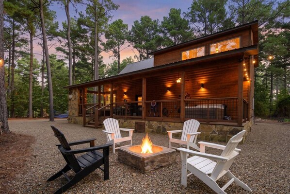 A cabin with a deck, outdoor seating, and a fire pit.