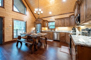 A spacious kitchen with wooden cabinets, a stainless steel refrigerator, and a granite countertop.
