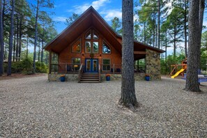 A lodge with a prominent wooden structure, a stone foundation, and a gravel driveway.