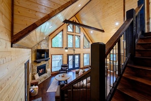 A spacious loft-style living area with a fireplace, leather seating, and a view of the outdoors.