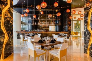 A bar area with a wine rack, seating with tables, and hanging spherical light fixtures. - Cancun All-Inclusive, Adults Only, Ocean Front Luxury Resort (Cancún)