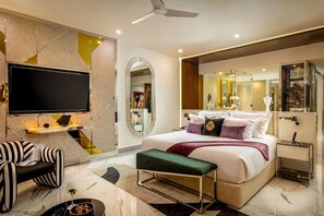 A modern hotel room with a large bed, a flat-screen TV, a seating area with a sofa and armchair, and a bathroom with a large mirror. - Cancun All-Inclusive, Adults Only, Ocean Front Luxury Resort (Cancún)