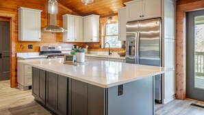Una cocina moderna con una isla grande, electrodomésticos de acero inoxidable y techo de madera.