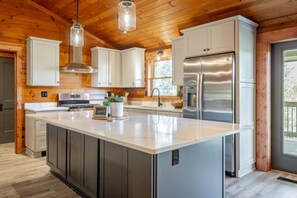 Una cocina moderna con una isla grande, electrodomésticos de acero inoxidable y techo de madera.