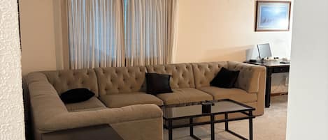 Una sala de estar con un sofá modular, una mesa de centro y una mesita auxiliar.
