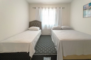 A room with two single beds, a window with curtains, and a view of the outdoors. - Budget Apartment in Zona 7 Maringa - AL09 (Maringá)