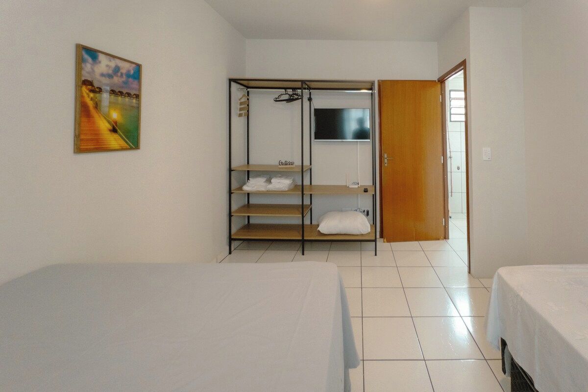 Une chambre d’hôtel avec deux lits, une armoire, un tableau et une fenêtre.